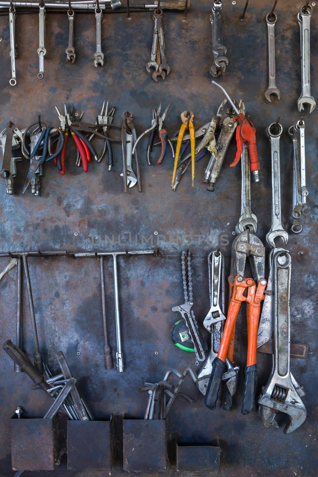 Old tools hanging on metal wall in workshop