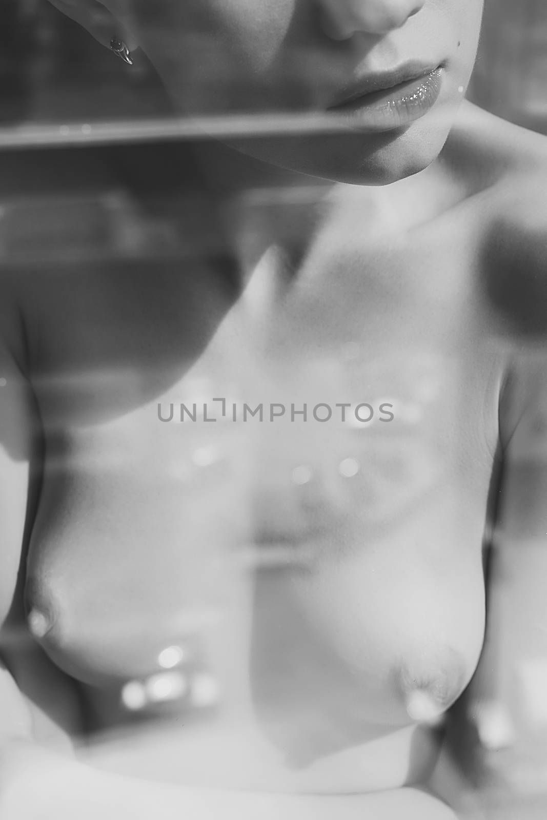 Crop view through glass of anonymous young woman with naked chest