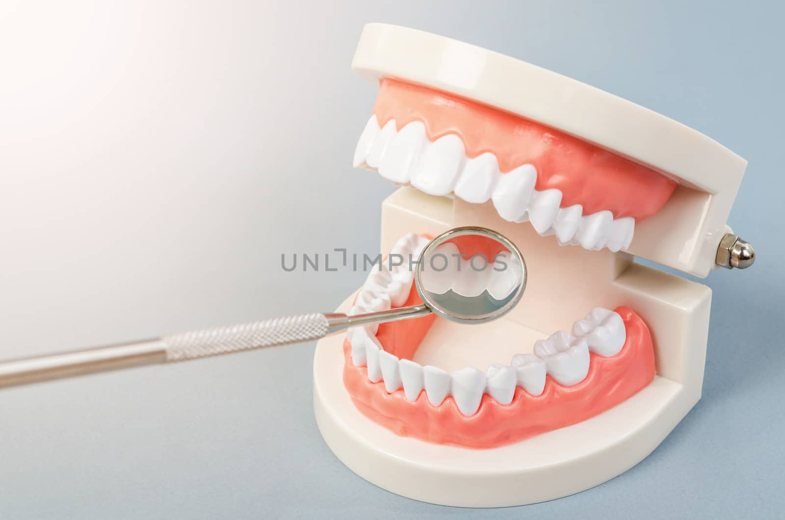 Mirror dentist equipment with model teeth on grey background. Dentist apoointment concept.