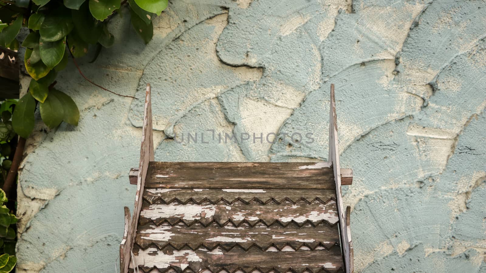 Wooden Roof Pattern with Peeling White Paint on Rough Painted Teal Wall - Green Leaves from the Garden - Miniature Wood Temple/ Spirit House in front of Local Home. Rural Thailand.