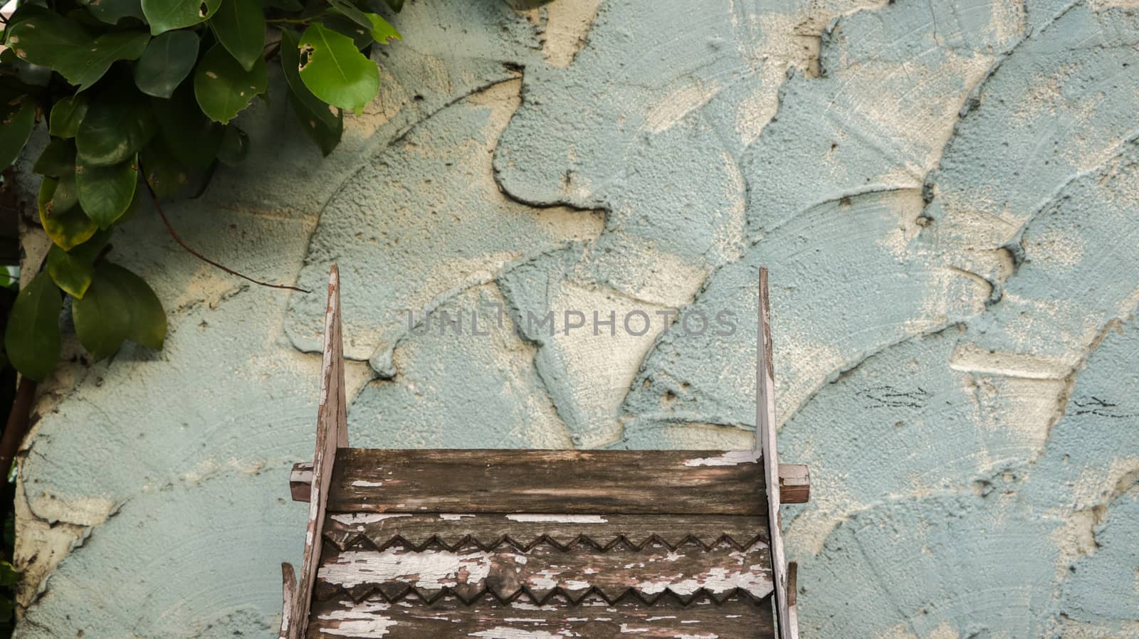 Wooden Roof Pattern with Peeling White Paint on Rough Painted Teal Wall - Green Leaves from the Garden - Miniature Wood Temple/ Spirit House in front of Local Home. Rural Thailand.