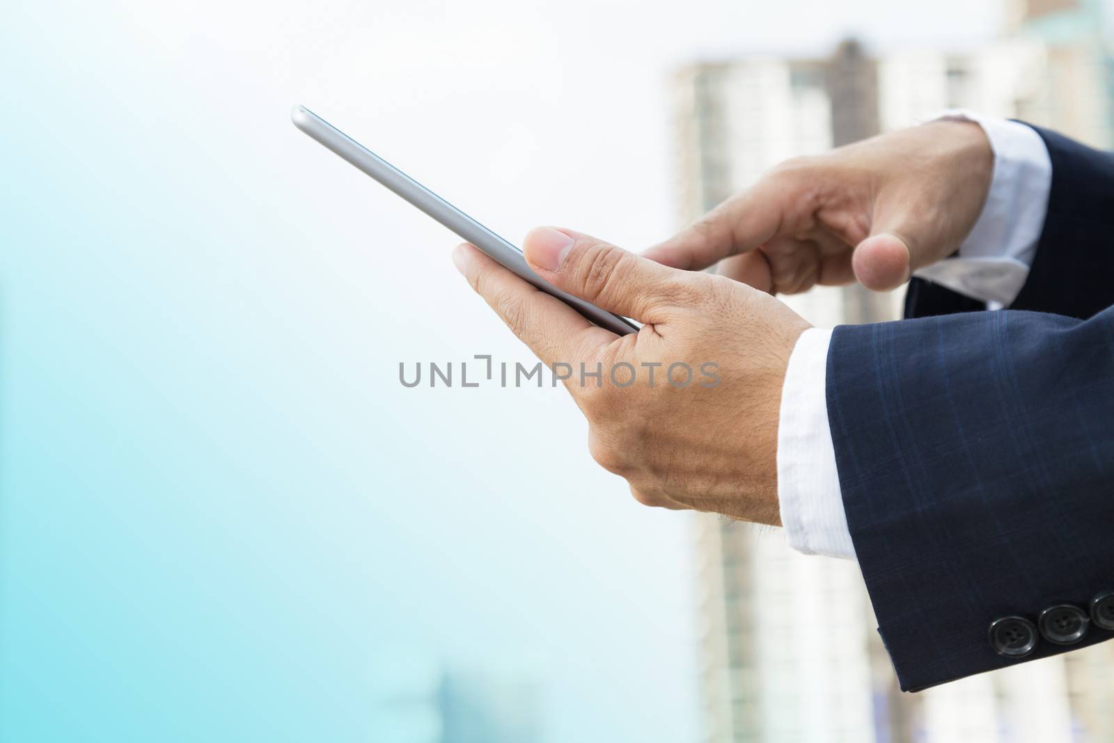Hands of businessman working on digital tablet outdoor