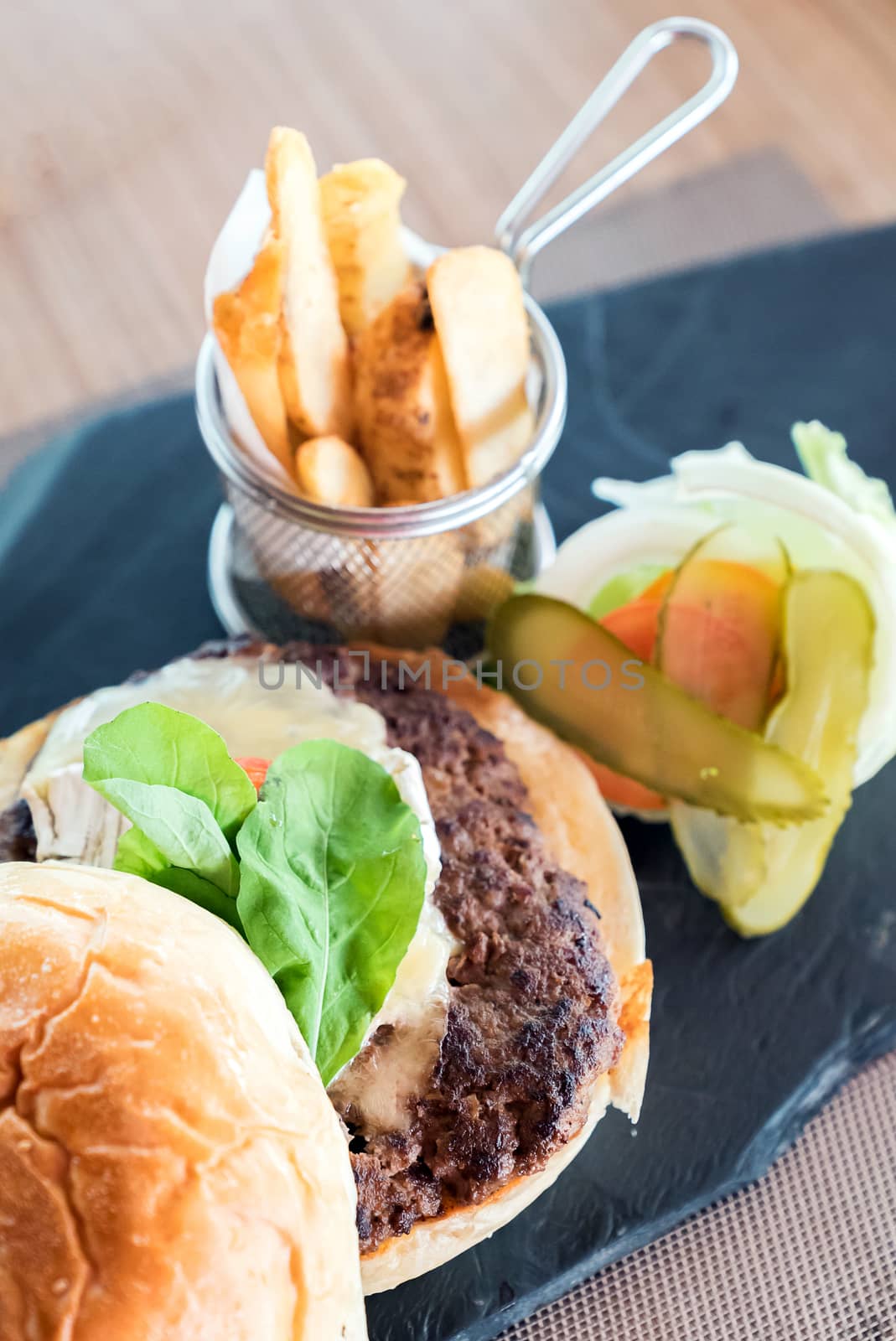 Homemade overload beef hamburger with fresh vegetables and cheese with fries
