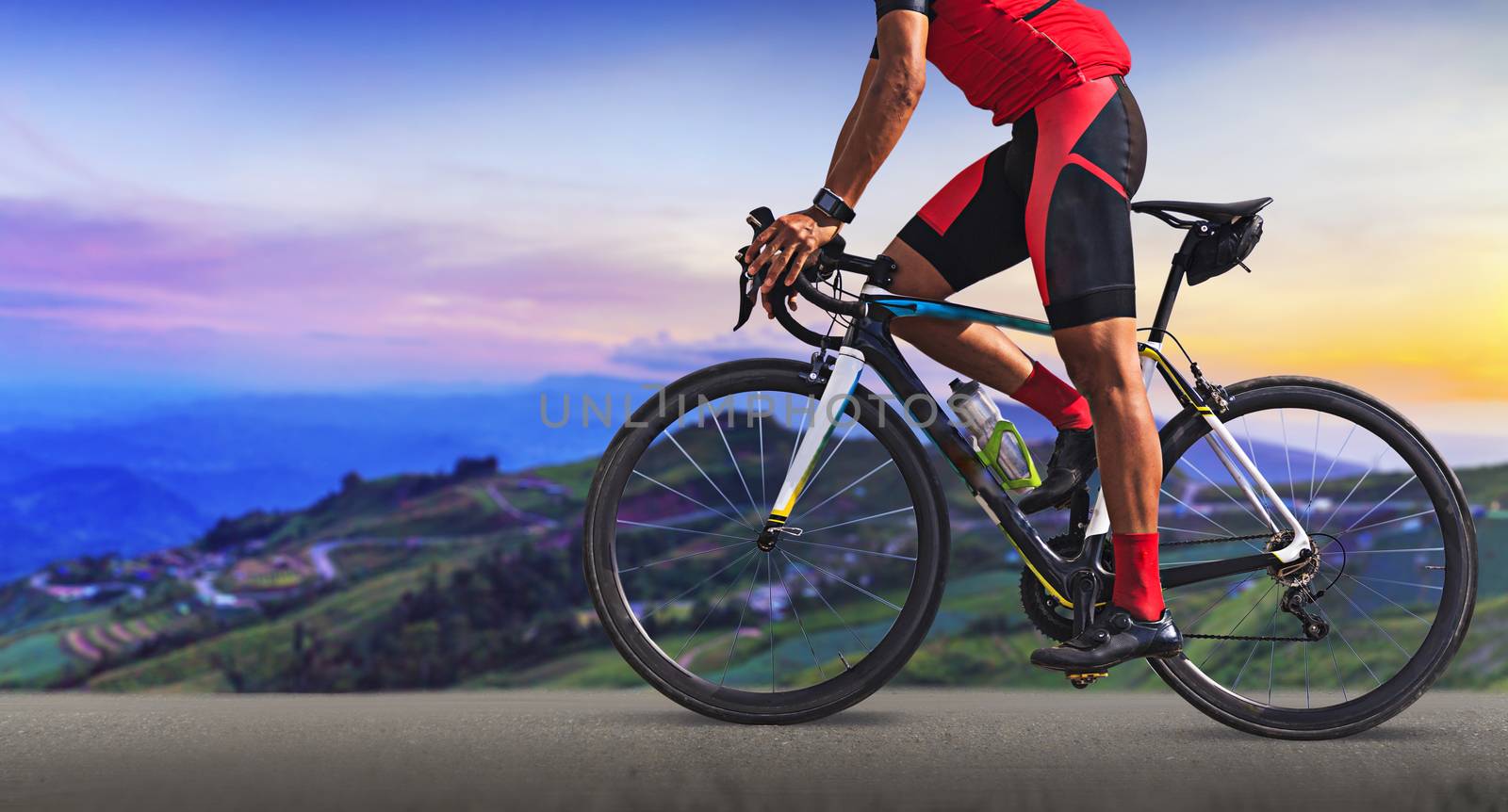 Man on a bicycle on a road between the beautiful mountains