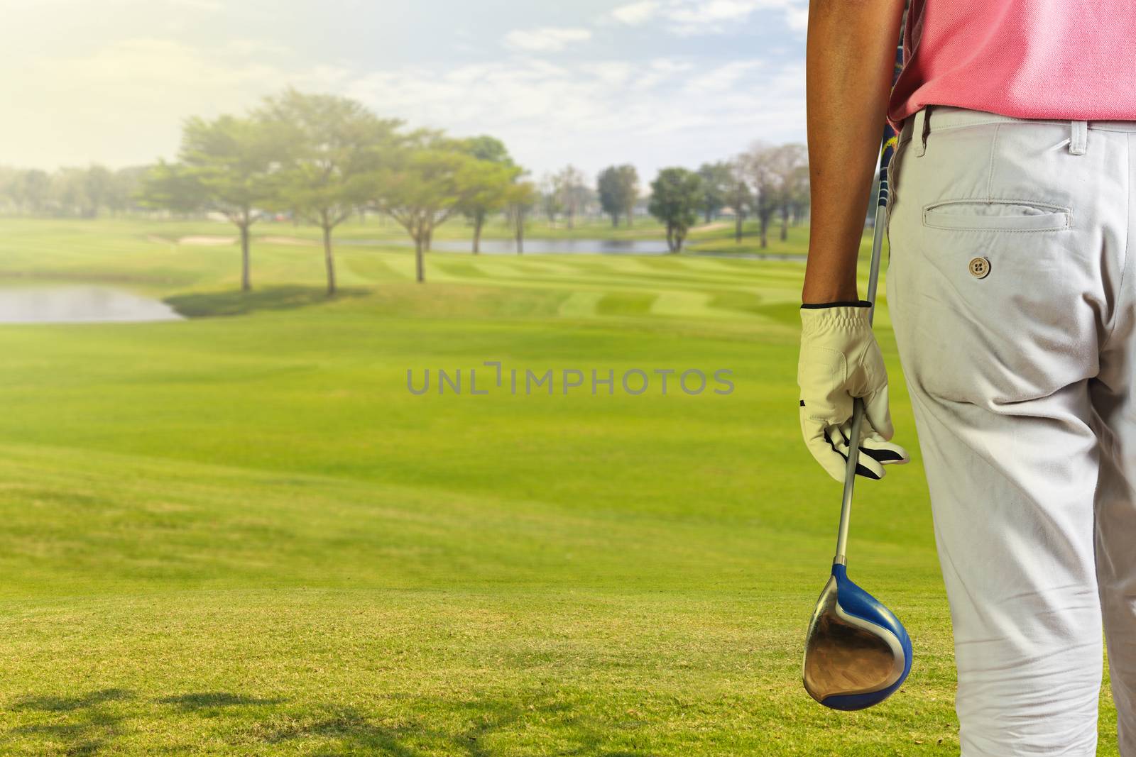 Golf player holding a golf club in golf course by Naypong