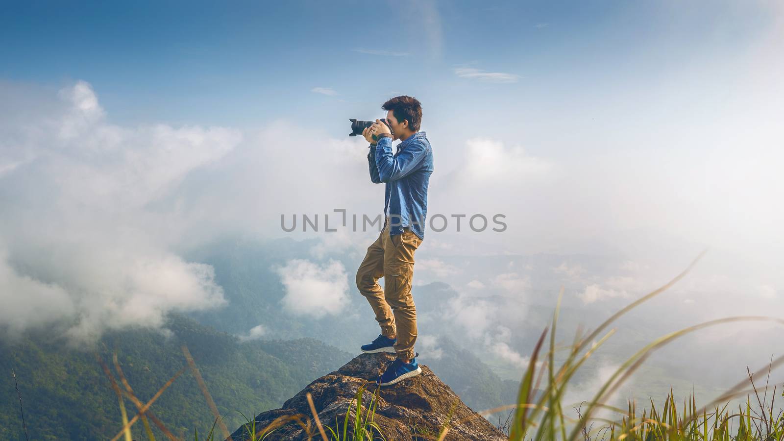 Photographer hand holding camera and standing on top of the rock in nature. Travel concept. Vintage tone.