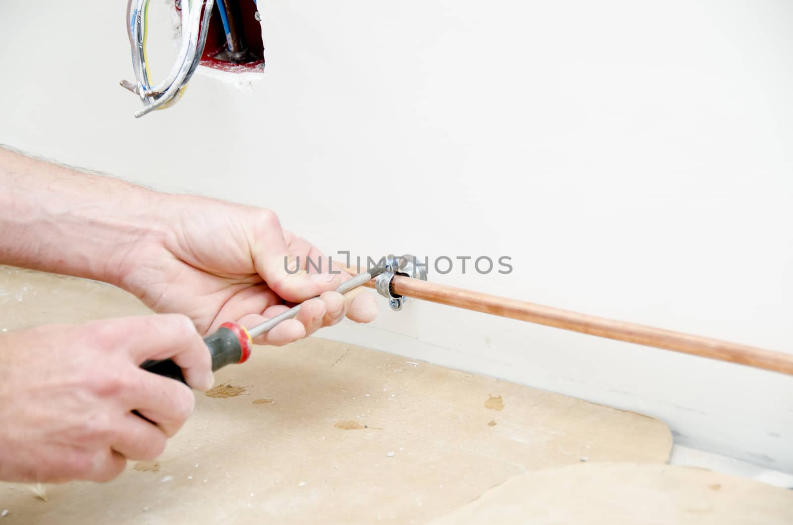 plumber fixing a copper pipe with a screwdriver