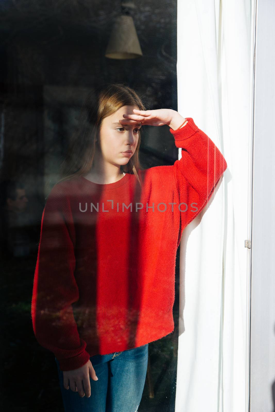 A sad and depressed cute little girl alone near the window. Outdoor portrait of a sad teenage girl.