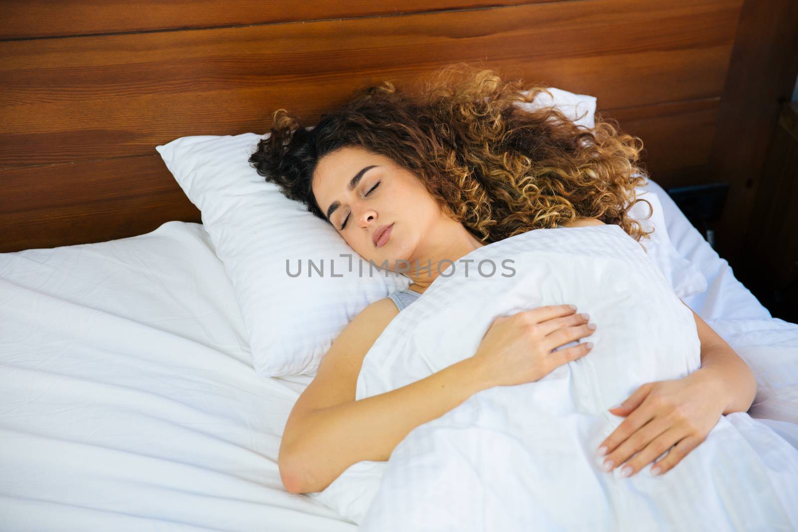 Young beautiful woman sleeping in her bed and relaxing in the morning, she is resting with eyes closed.