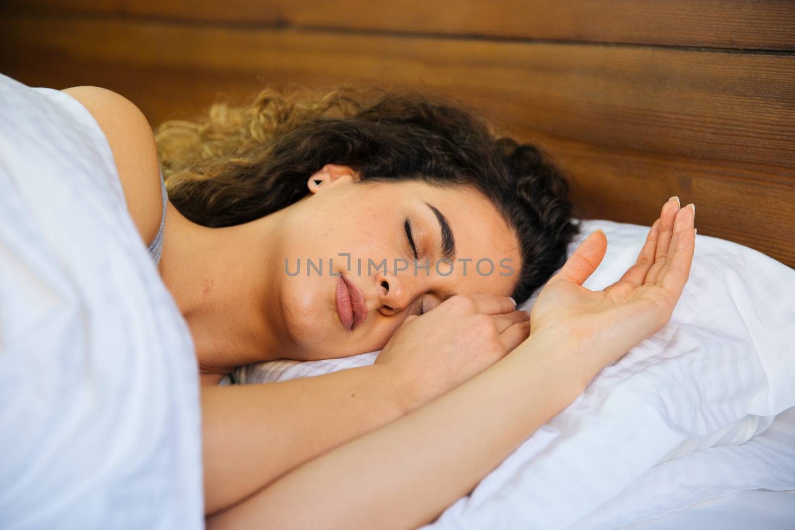 Young beautiful woman sleeping in her bed and relaxing in the morning, she is resting with eyes closed.