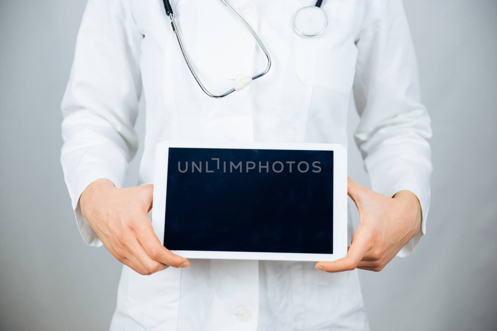 Female doctor holding blank digital tablet isolated on black background with clipping path for the screen.