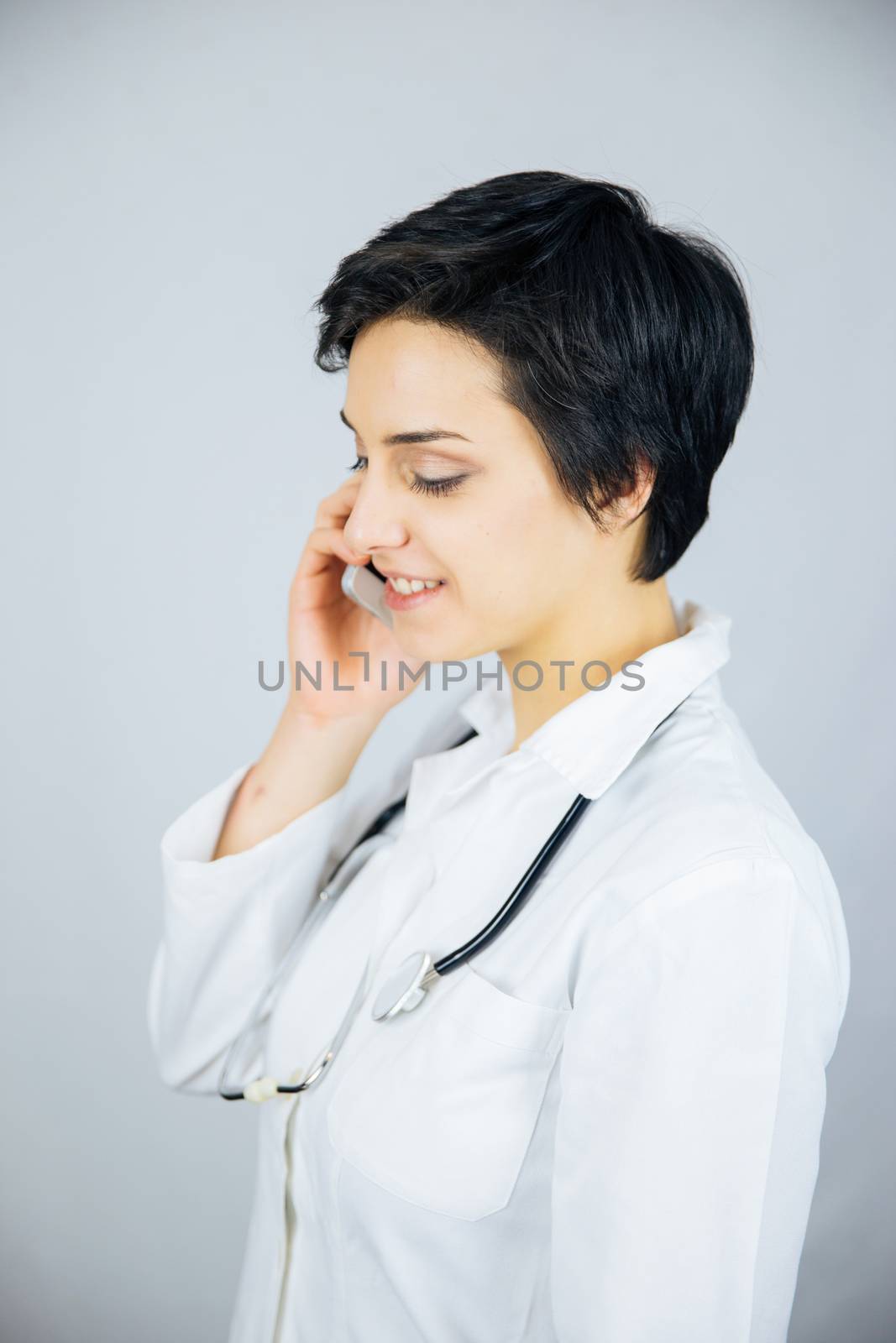 Female doctor talking on the cell phone isolated on white background.
