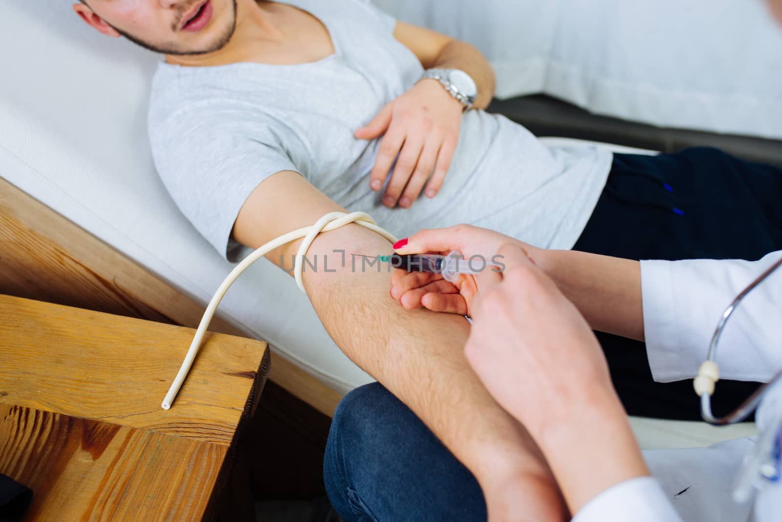 Female doctor taking a blood from male patient at the private clinic