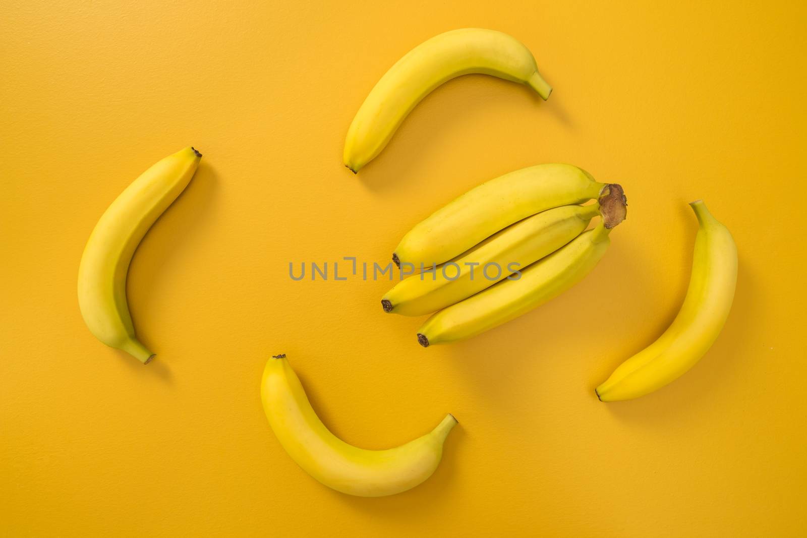 Bananas on bright yellow background by anikasalsera