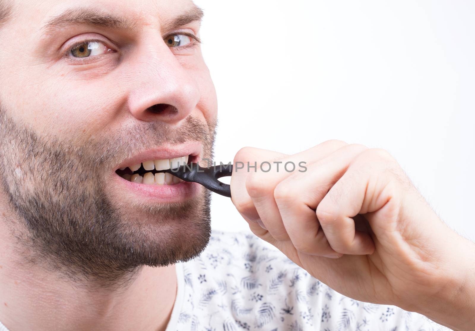 Man eating typicaly dutch candy called 'Dropsleutel' (candy key) - Isolated