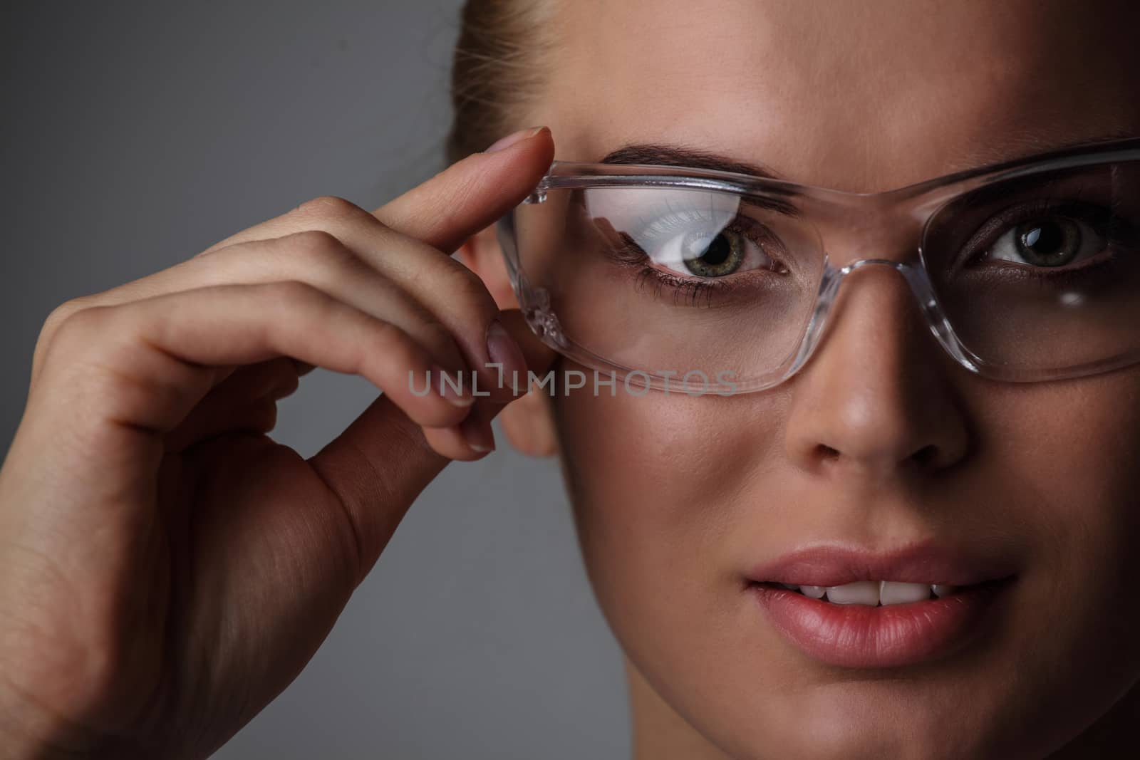 Beautiful woman with transparent futuristic glasses on gray background