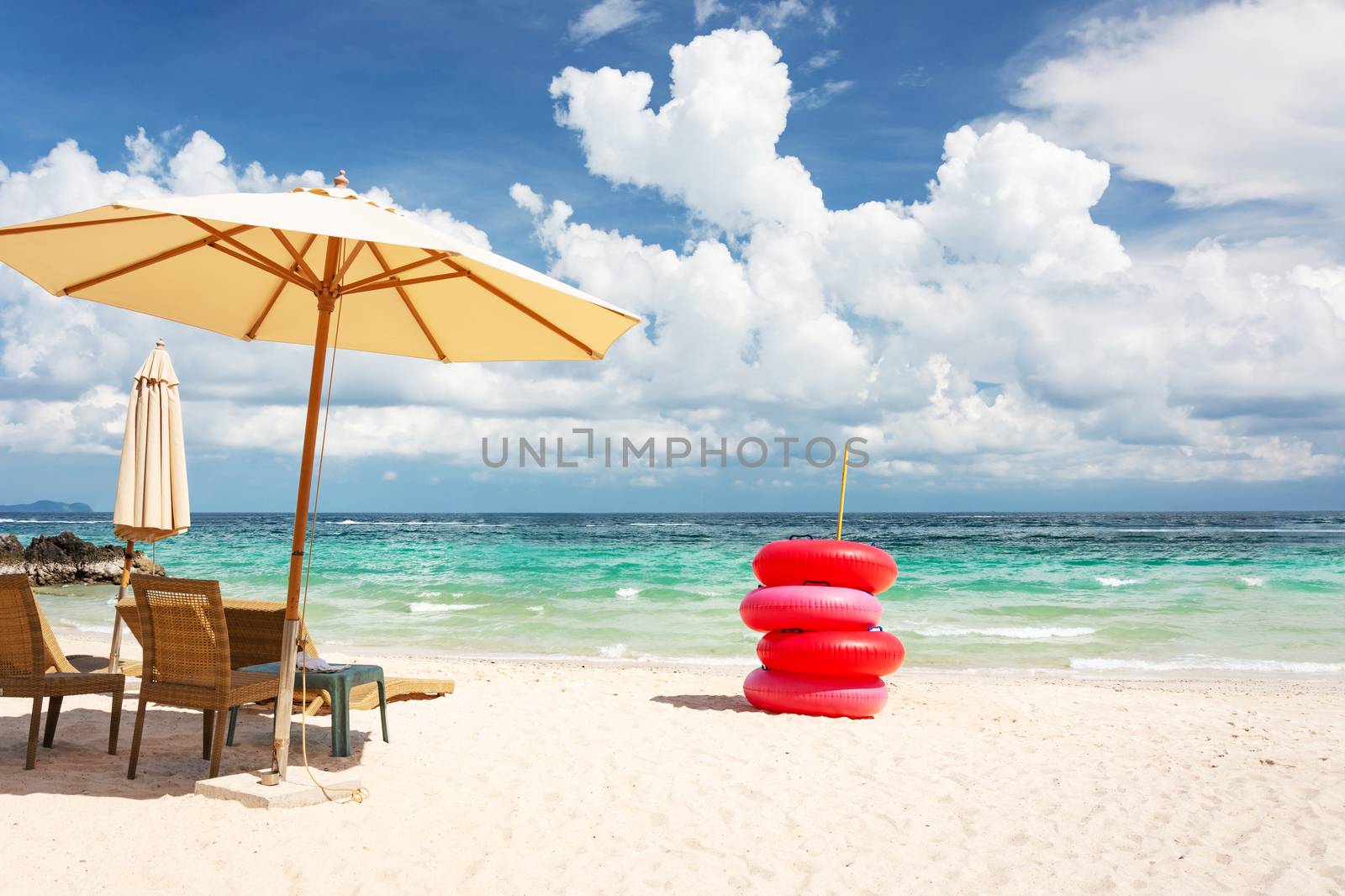 Beach Chair, Umbrella And Red Life Buoy On The Beach And The Bright Green Sea, On A Good Day.