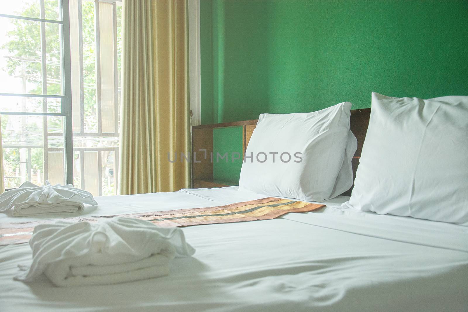 White pillows and white towels on bed in green wall room by rakoptonLPN