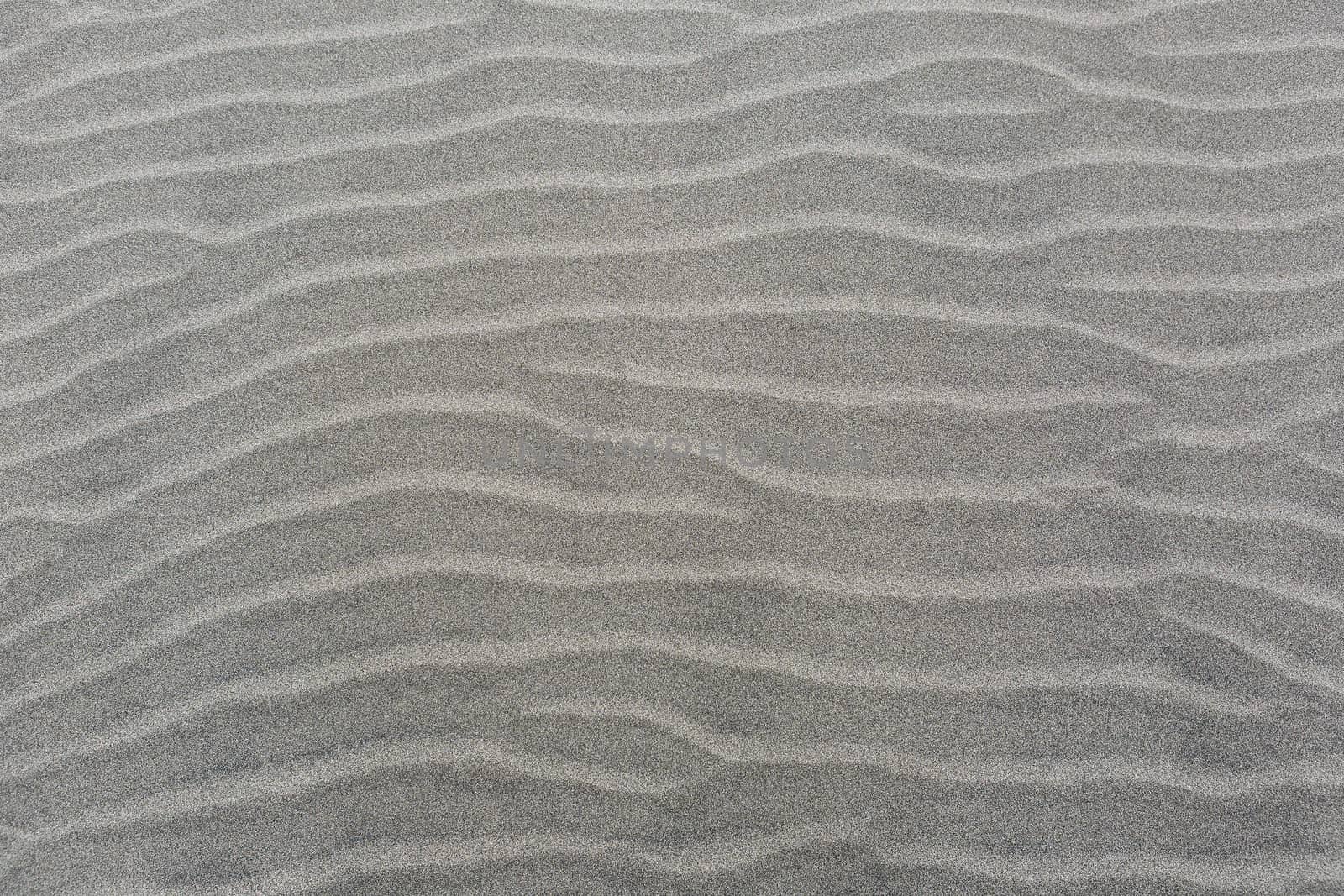 Windswept sand dune wavy lines pattern on sandy beach background