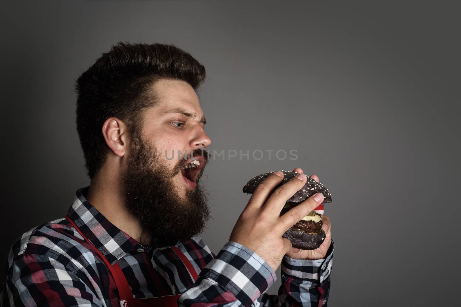 Man biting black hamburger by destillat