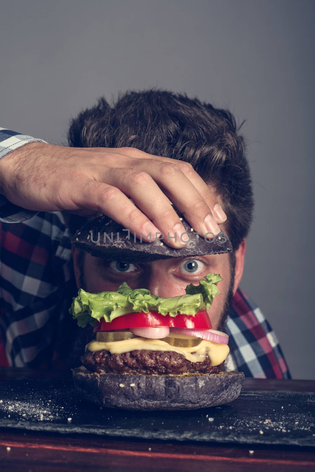 Man cooking fresh self made black burger close up