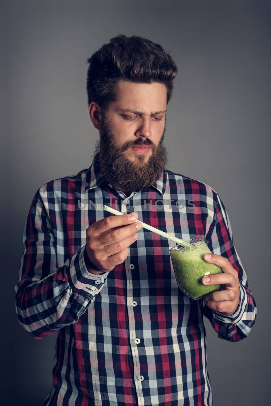 Young Man looks incredulously at healthy eating green spinach smoothie