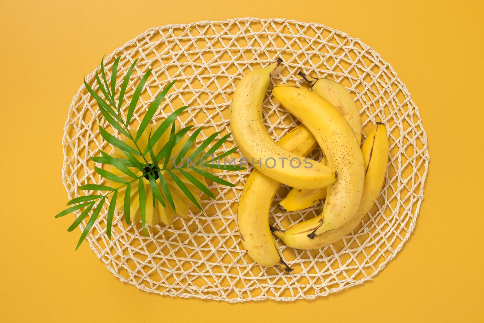 Ripe bananas and palm leaves on yellow background by anikasalsera