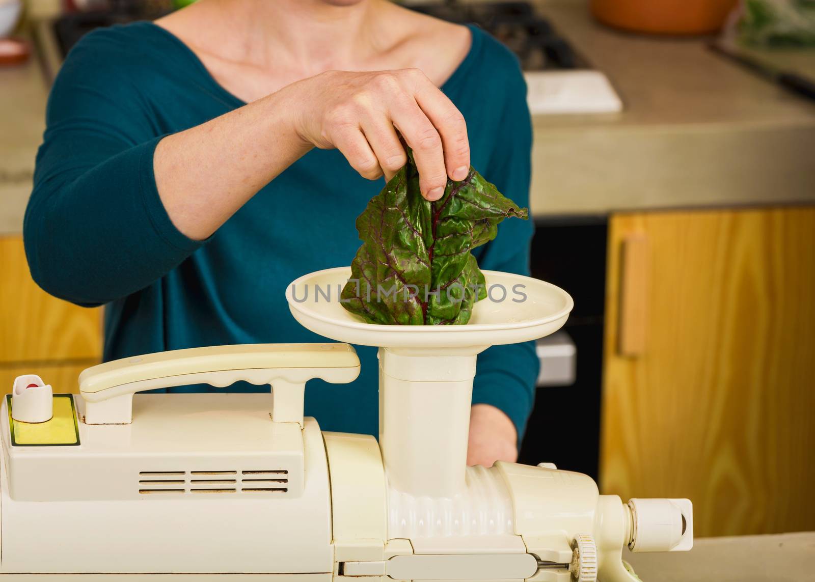 Woman using a centrifuge machine to prepare a detox juice. 