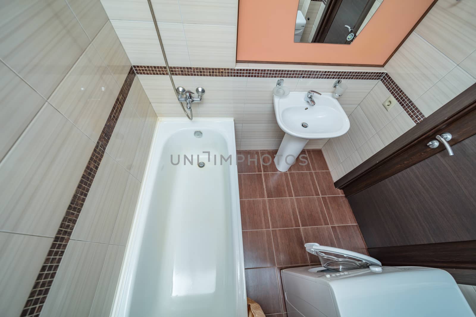 Small beige tile bathroom with bath tube sink and washing machine