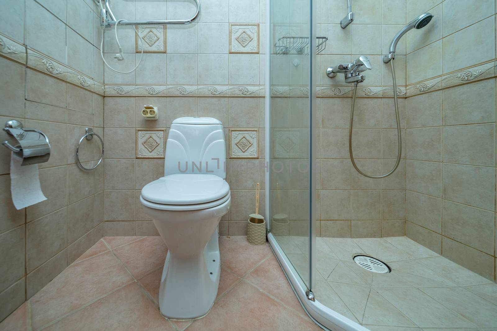 Toilet bowl in small bathroom with shower Room with brown tile decoration