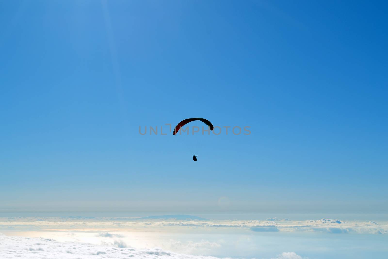 Paraglider flying over clouds in a summer day