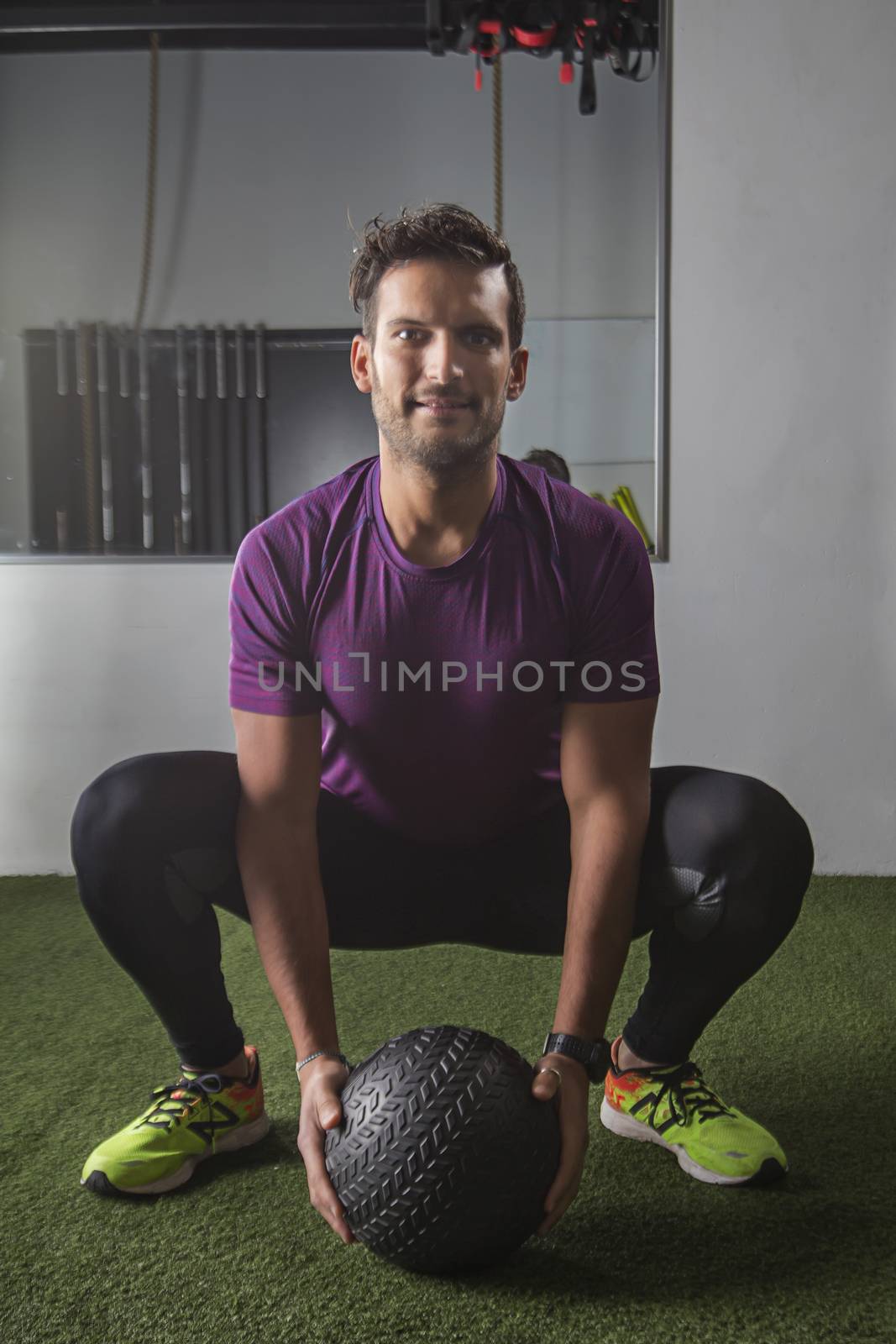 Young men squatting and holding a small black medicine ball