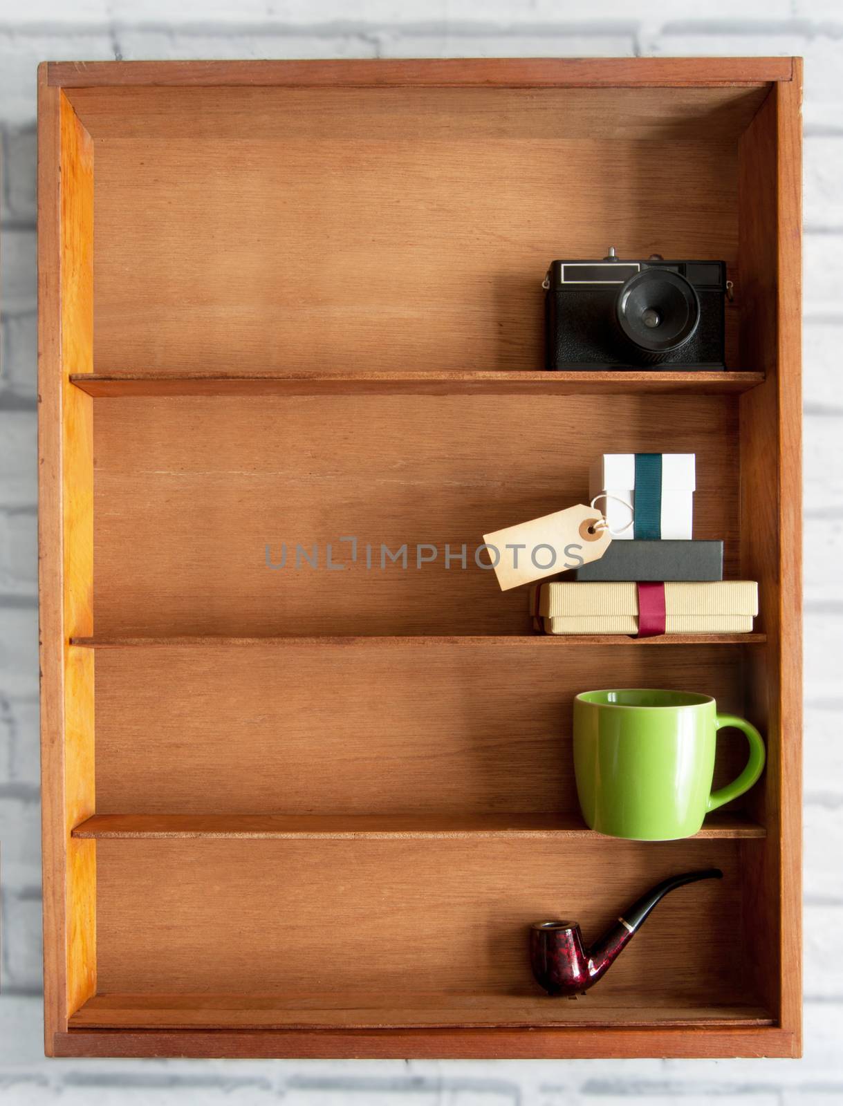 Gift box with blank label inside a display shelf with coffee cup and pipe