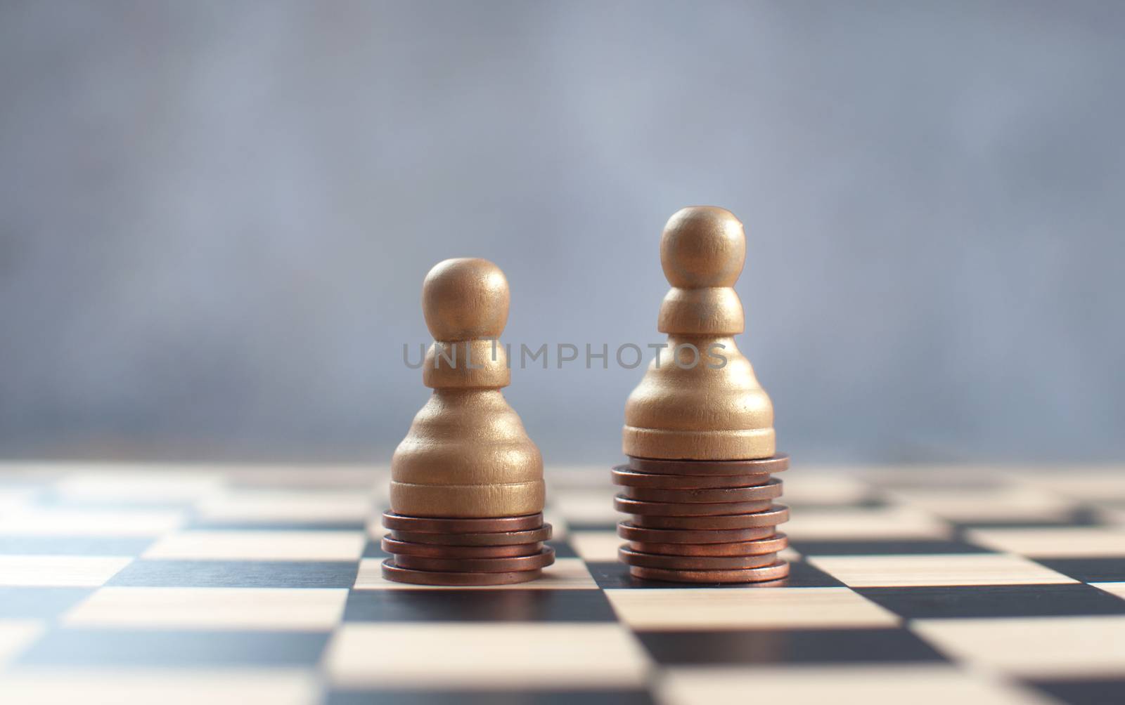 Two chess pawns with on top of a heap of coins 