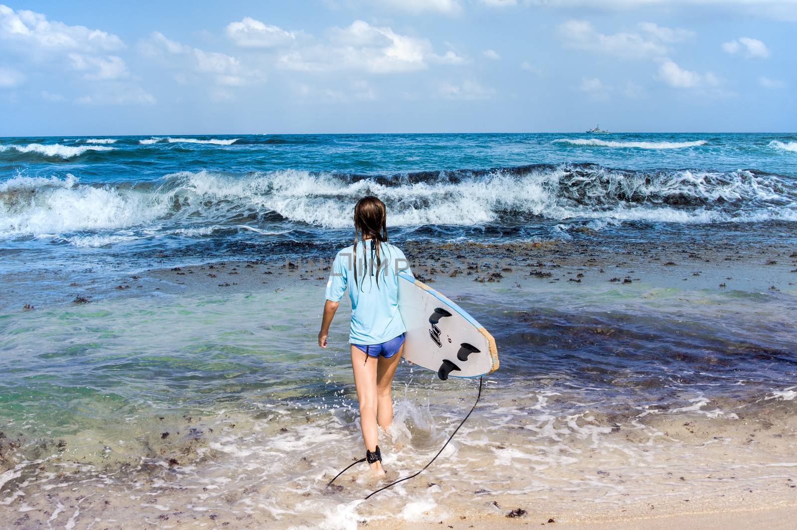 Young girl fearlessly goes into the sea to surf hoping to catch a big wave