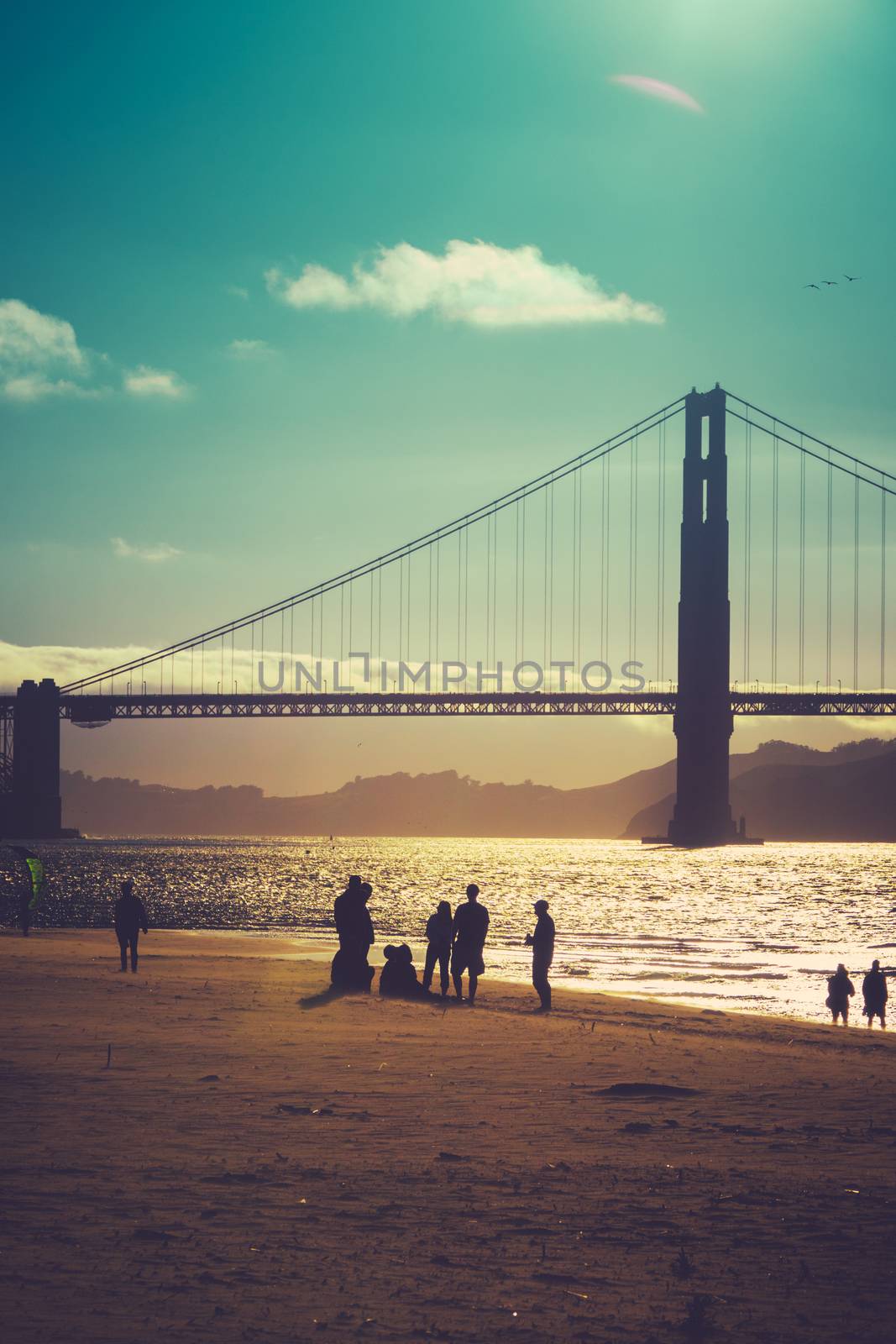 A Silhouetted Group Of Friends On The Beach Under Golden Gate Bridge San Francisco