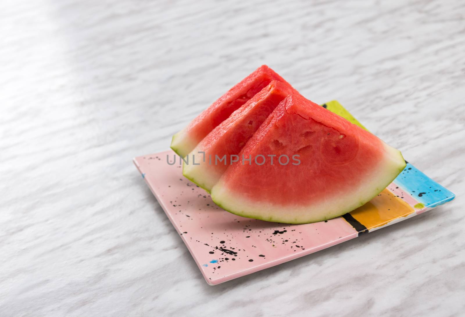 Slices of tasty watermelon on a ceramic plate, on marble background.