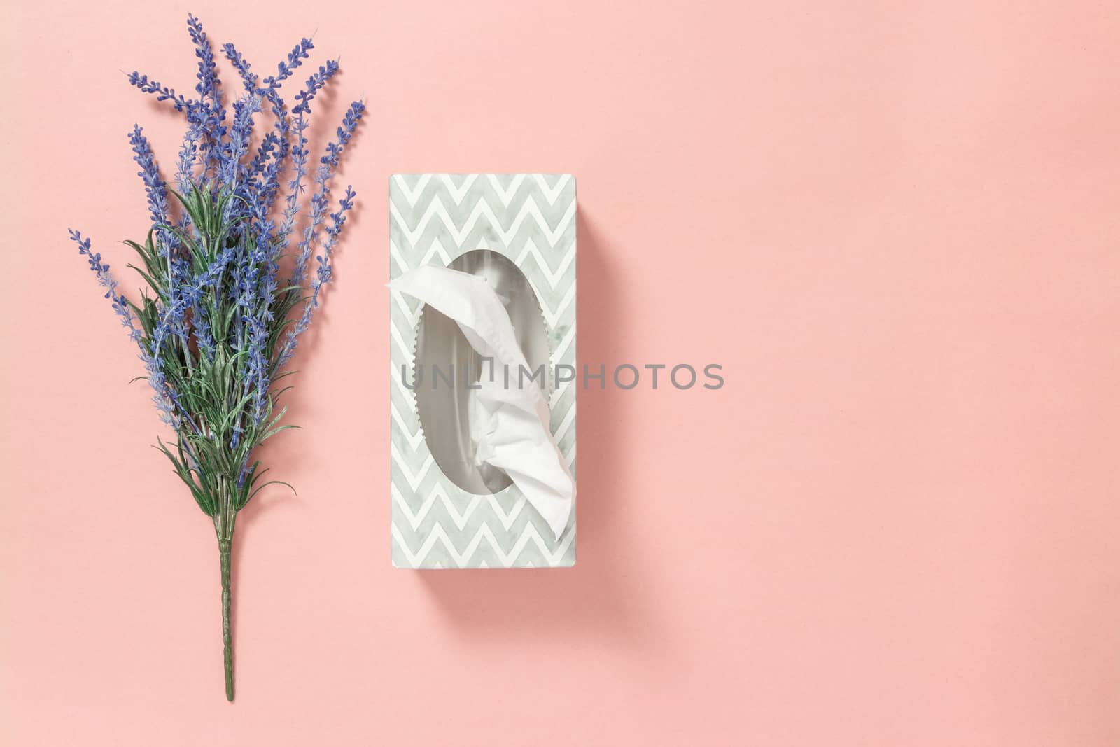 Gray tissue box and blue lavender on pastel pink background.