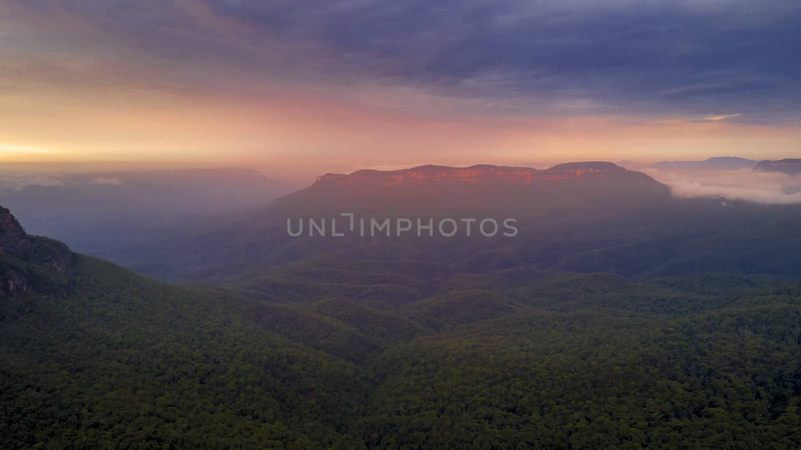 Beautiful sunrise over mist-filled Jamison Valley. In the distance Mt Solitary cliffs catch the warm light. Blue Mountains Australia