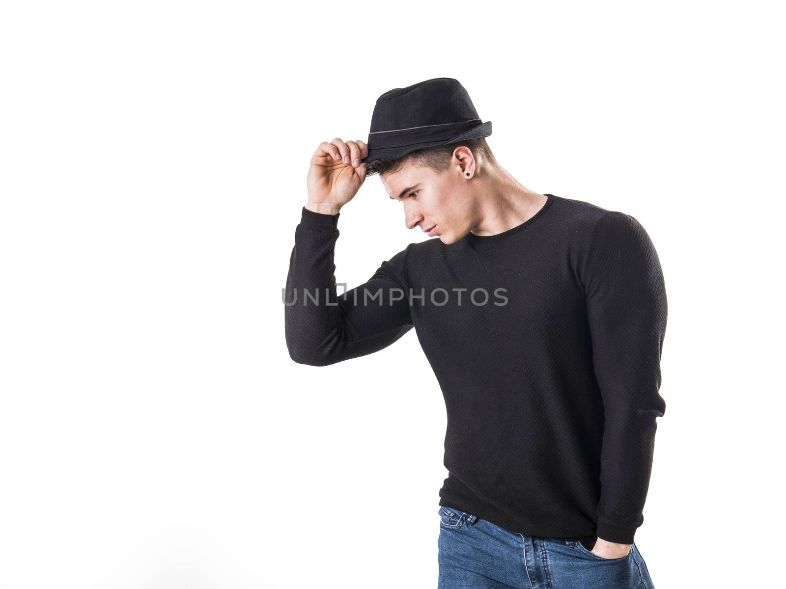 Handsome young muscular man looking down in studio shot, wearing fedora hat, isolated on white background