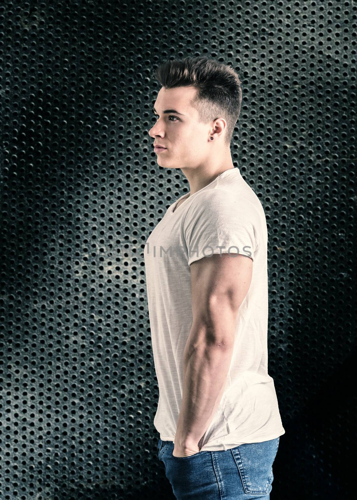 Handsome young muscular man looking to a side, in studio shot over neutral dark background