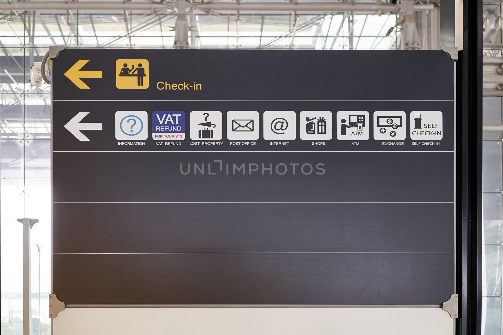 Check in and service guide information board sign with yellow and white character on black background at international airport terminal.