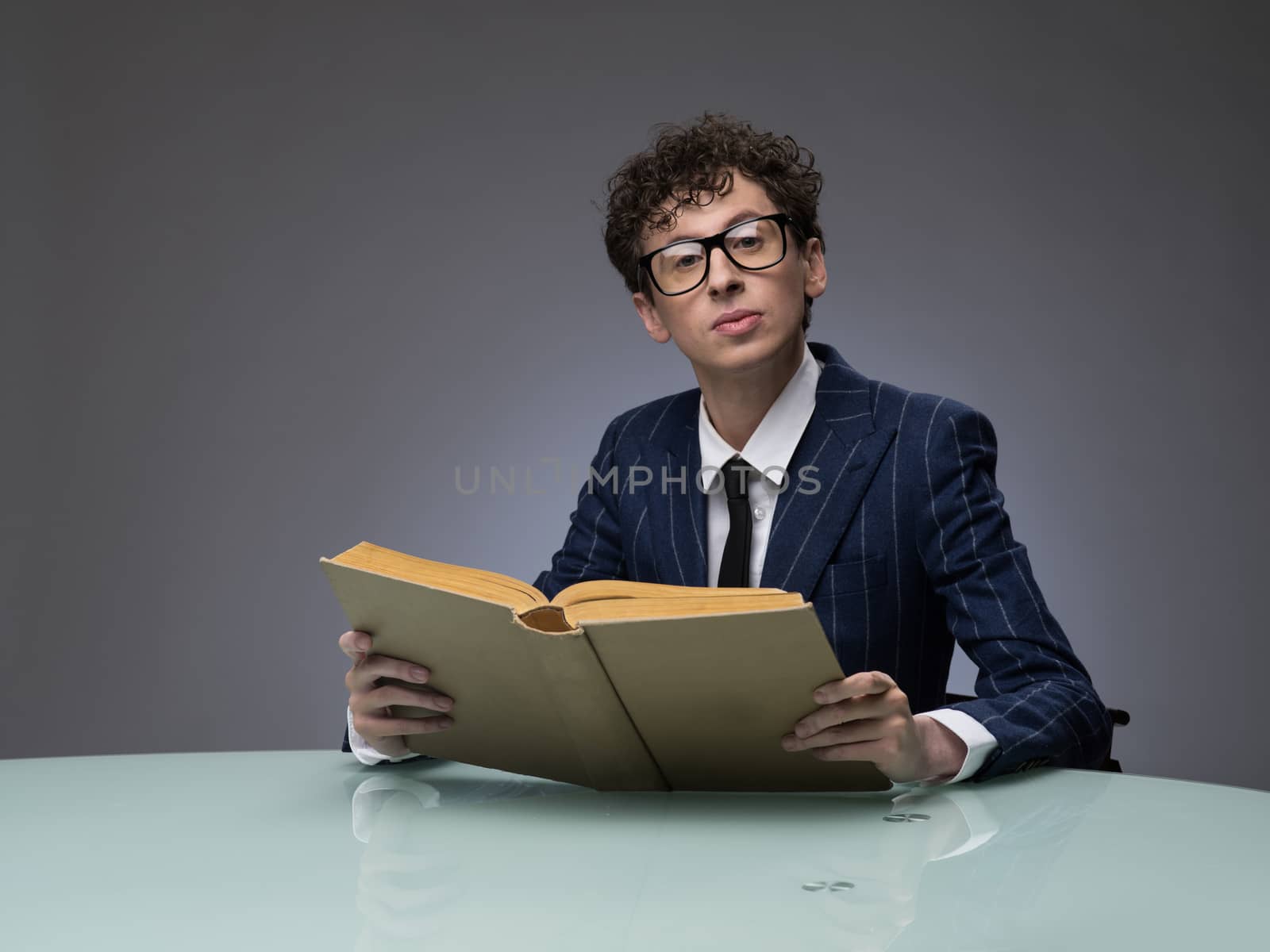 Funny man in striped suit reading a book over gray background. Professional actor facial expression.