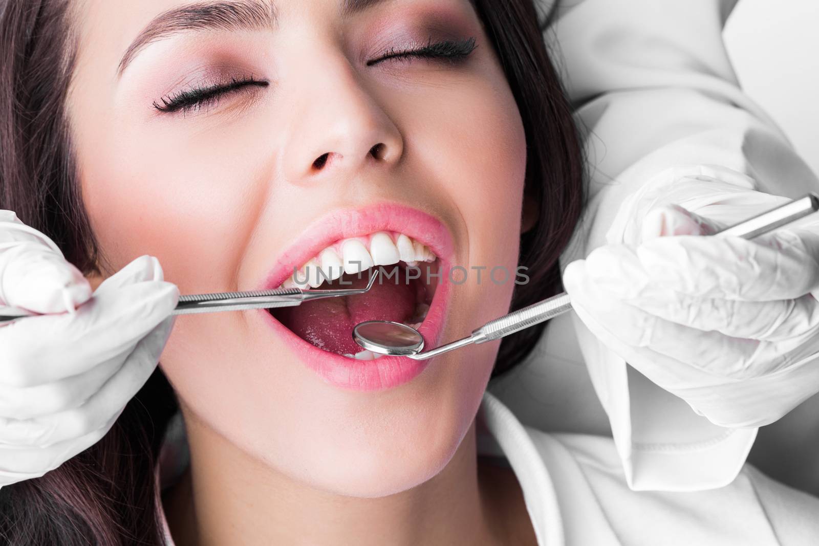 Dentist examines the teeth of beautiful female patient