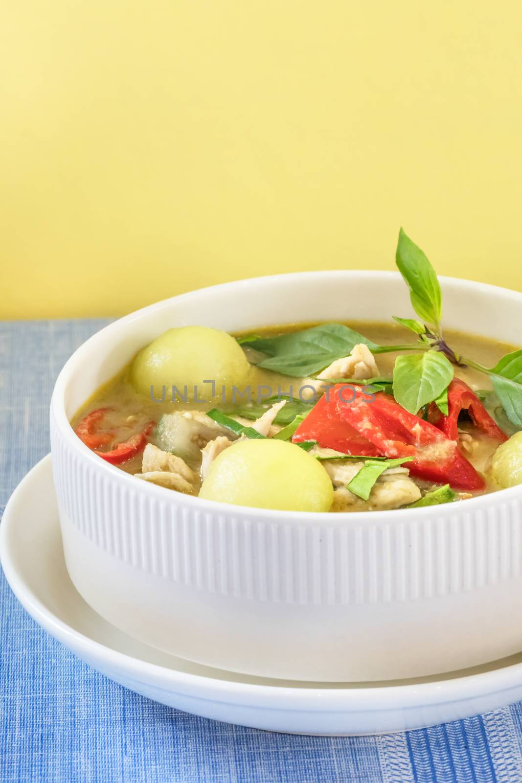 Green curry with chicken and mix vegetables in white bowl