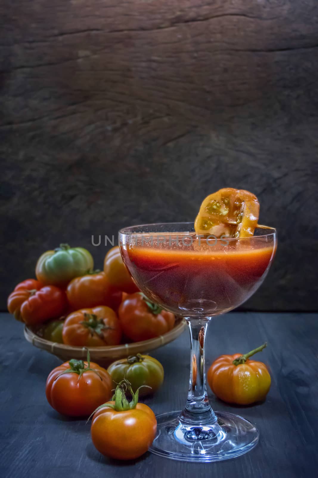 Glass of fresh tomato juice and tomatoes on a wooden table