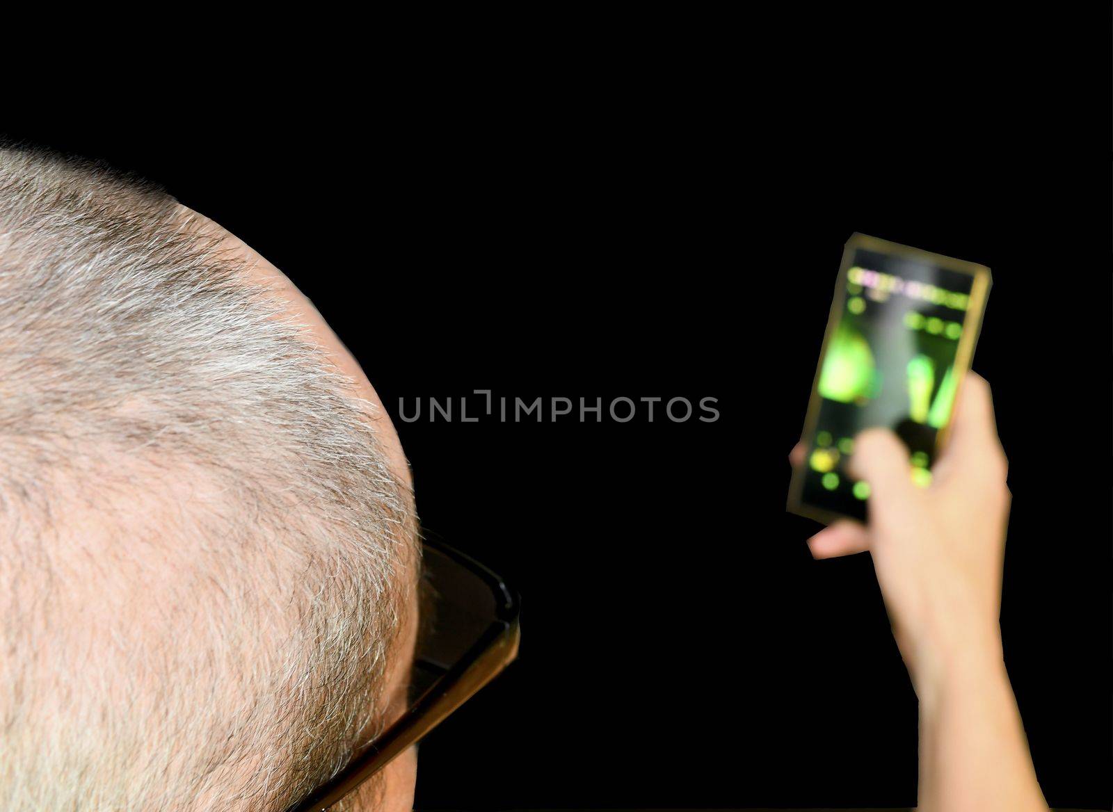 Middle aged man with glasses sitting in an armchair. Mature man with mobile phone on black background. Copy space. Senior concept by roman_nerud