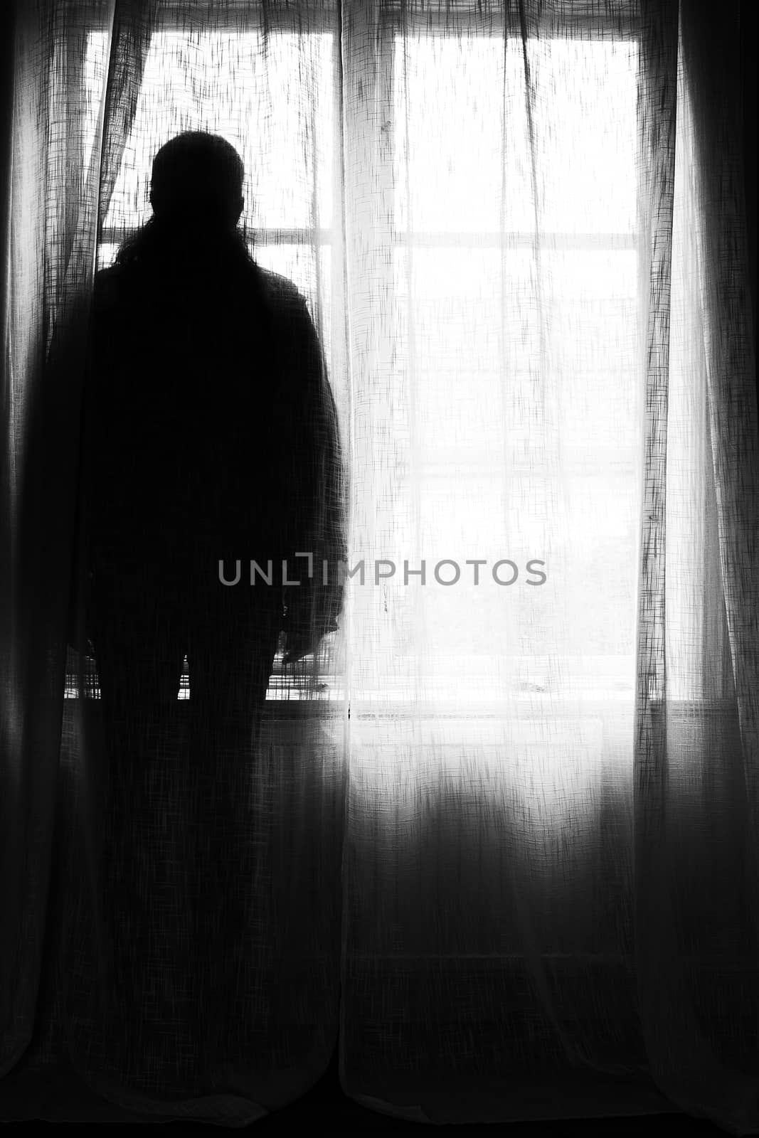 Sillhouette of a person standing in front of a window.