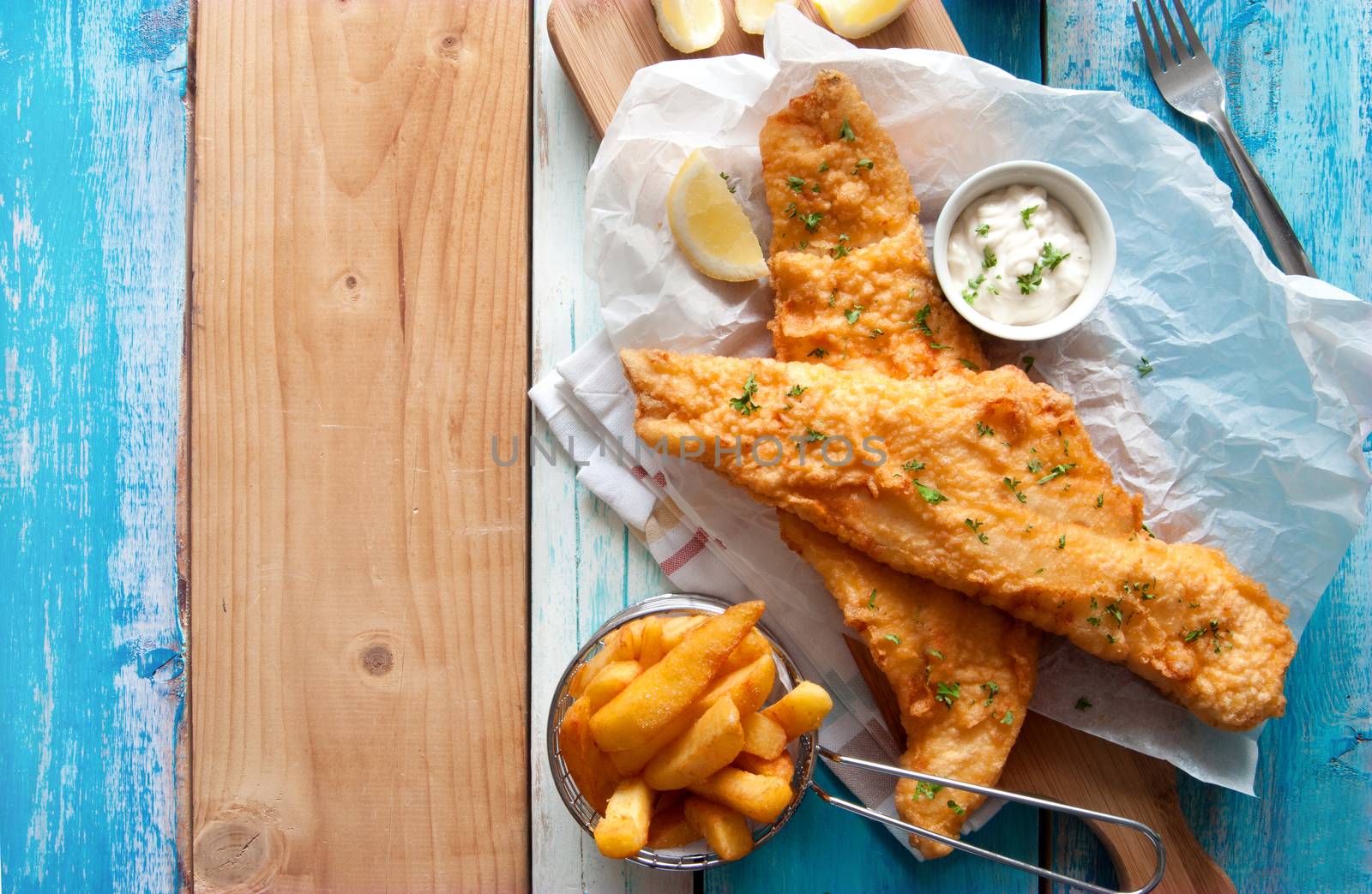 Traditional British fried fish in batter with chips in a basket 