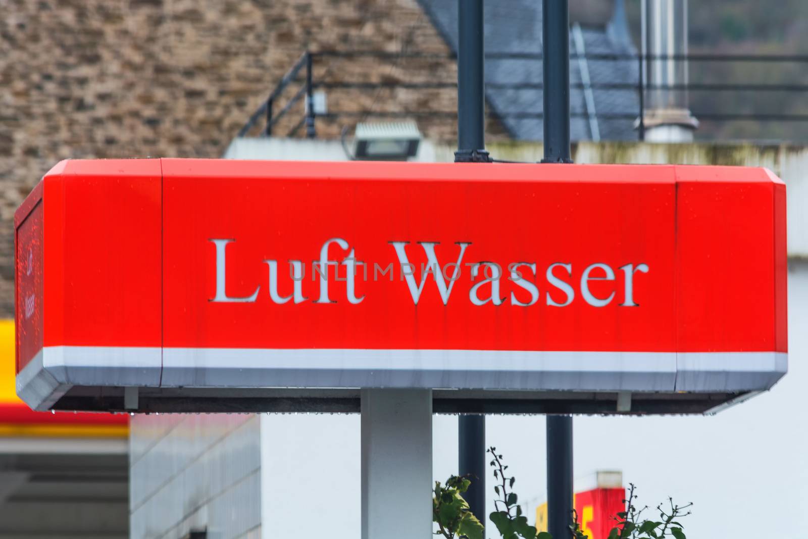 Red billboard with inscription in German "air and water" at a gas station.